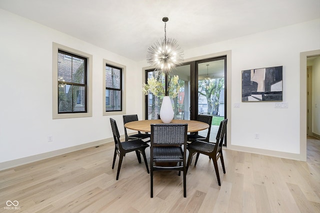 dining room featuring light wood-style floors, baseboards, and a notable chandelier