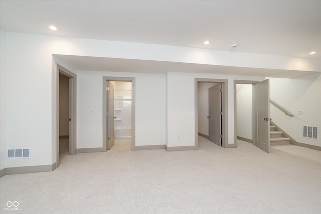 finished basement with light carpet, stairway, and visible vents