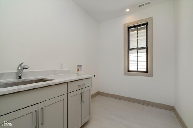 washroom featuring cabinet space, baseboards, visible vents, washer hookup, and a sink