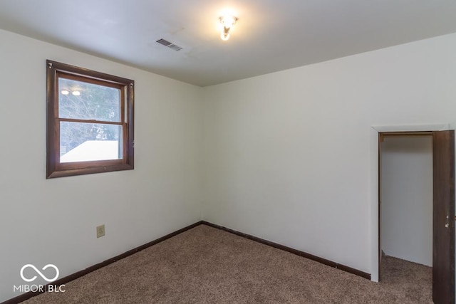 spare room featuring carpet, visible vents, and baseboards