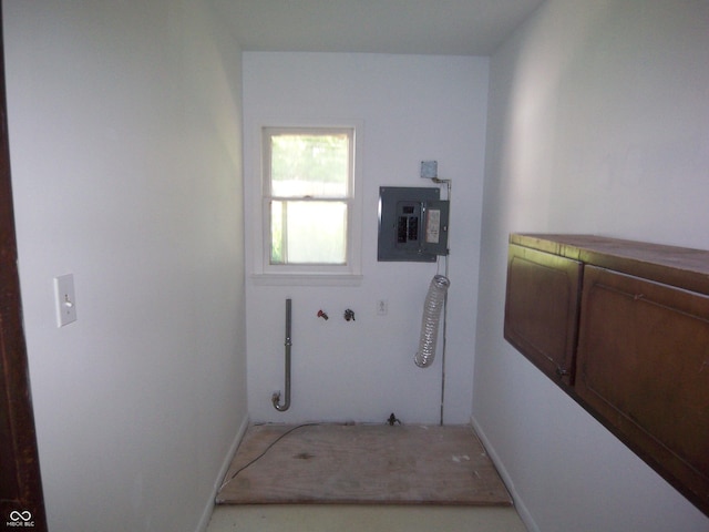 laundry area with electric panel and baseboards