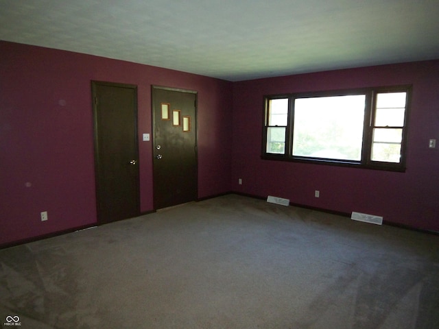 carpeted empty room featuring baseboards and visible vents