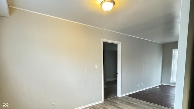 spare room with baseboards and wood finished floors