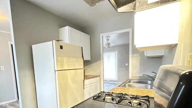 kitchen with white cabinets, freestanding refrigerator, and a sink