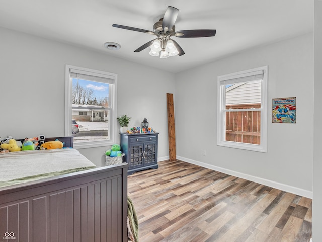 bedroom with light wood-type flooring, visible vents, baseboards, and multiple windows