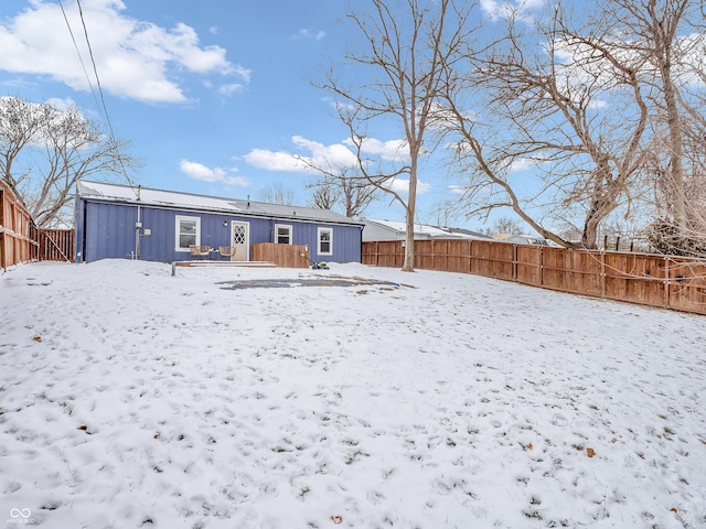 snow covered back of property with a fenced backyard