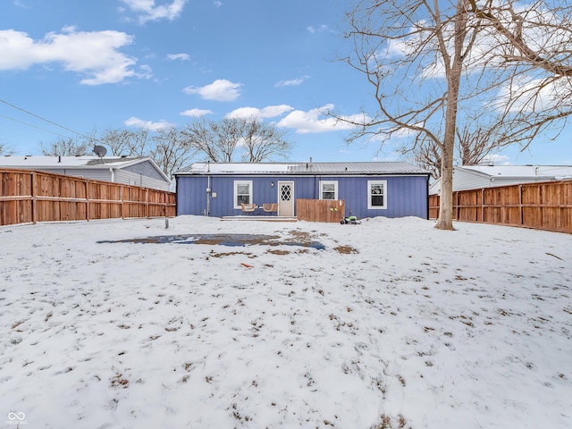 snow covered house featuring fence and board and batten siding