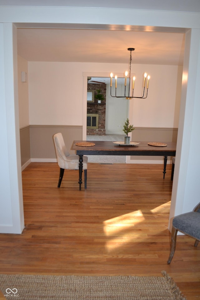 dining area featuring a fireplace, an inviting chandelier, and wood-type flooring