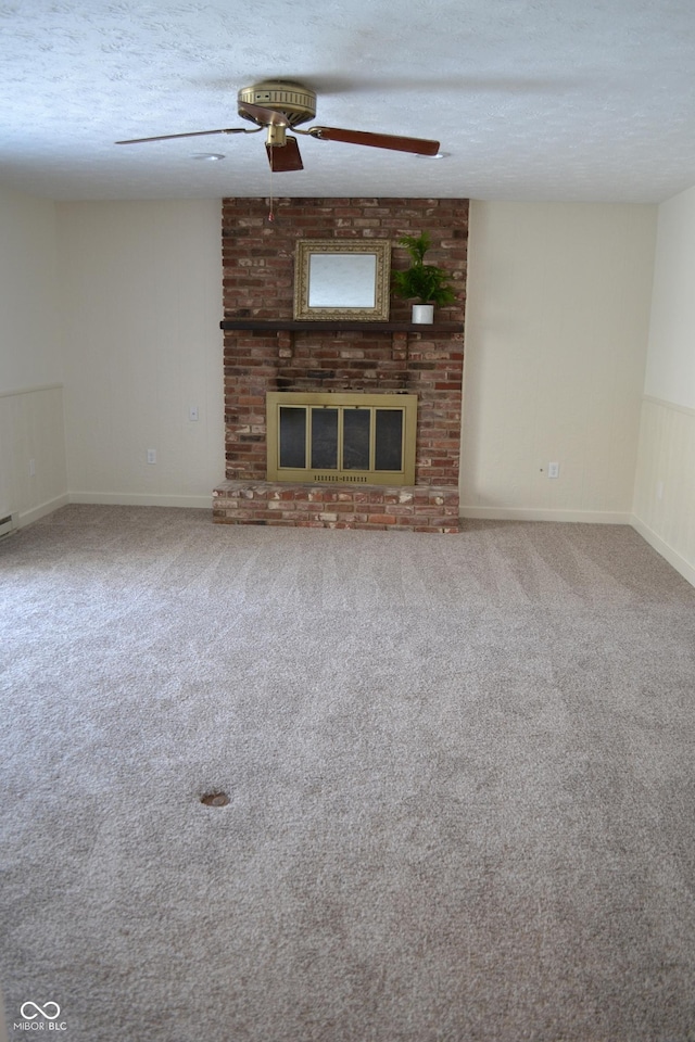 unfurnished living room featuring ceiling fan, carpet, a brick fireplace, and a textured ceiling