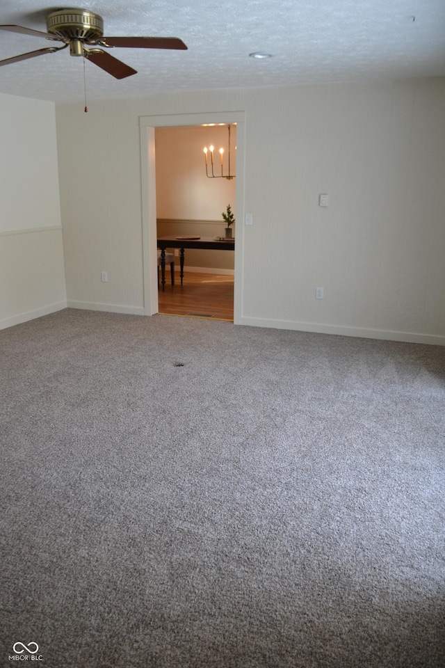 empty room with ceiling fan with notable chandelier, carpet floors, and a textured ceiling