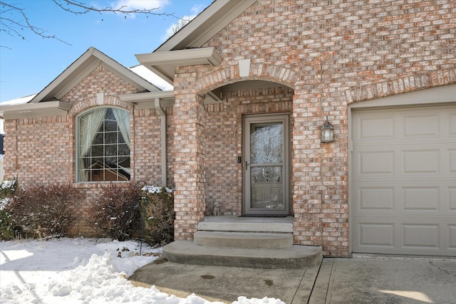 snow covered property entrance featuring a garage