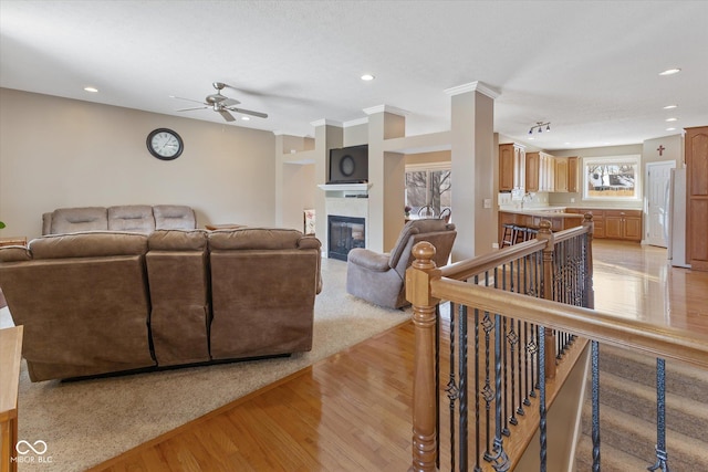 living room featuring ceiling fan, light hardwood / wood-style flooring, sink, and crown molding