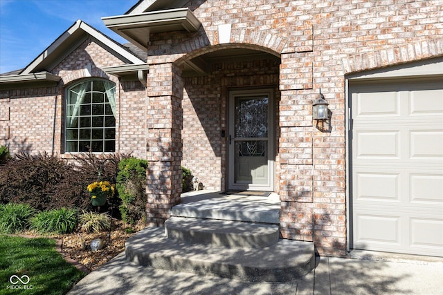 view of exterior entry with brick siding and a garage