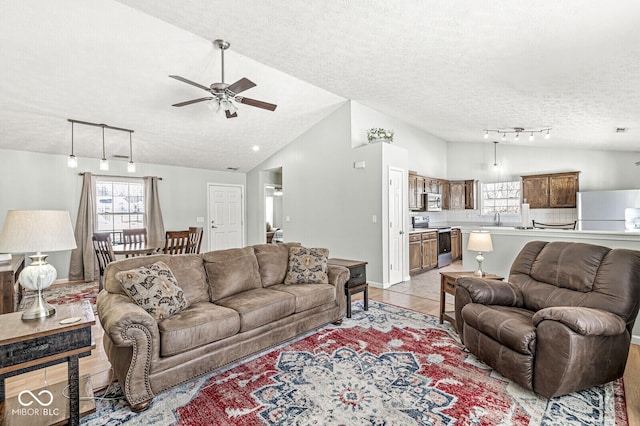 living room featuring light tile patterned floors, lofted ceiling, a ceiling fan, a textured ceiling, and baseboards