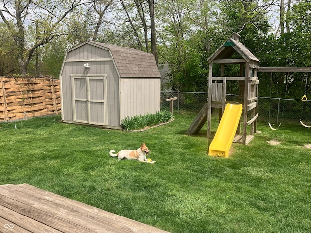 view of playground featuring a fenced backyard, a shed, an outbuilding, and a yard