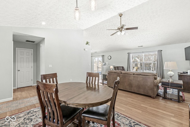 dining area featuring lofted ceiling, ceiling fan, a textured ceiling, visible vents, and light wood finished floors