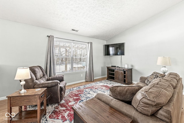 living room featuring lofted ceiling, a textured ceiling, wood finished floors, visible vents, and baseboards