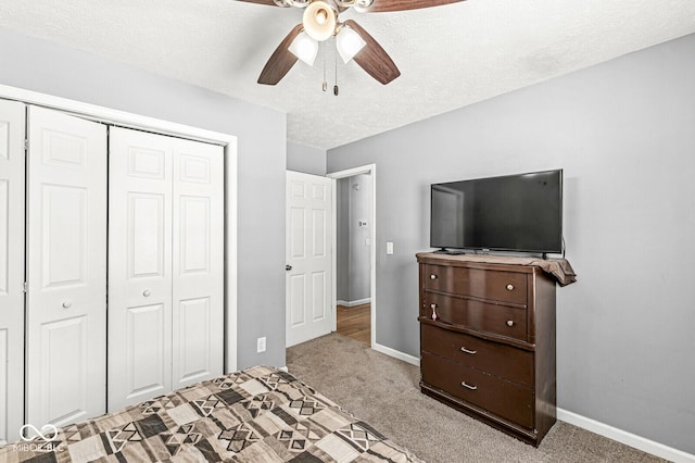 bedroom with a closet, light colored carpet, a textured ceiling, and baseboards