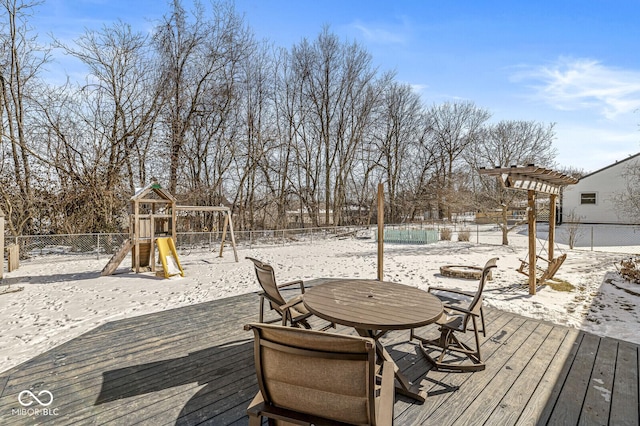 snow covered deck with playground community, fence, and a pergola