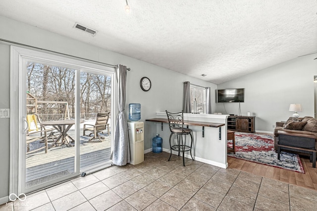 kitchen featuring visible vents, a kitchen breakfast bar, open floor plan, a peninsula, and vaulted ceiling