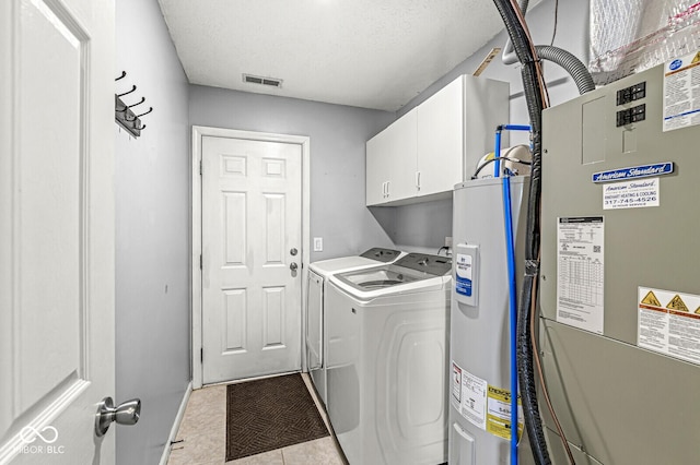 laundry room with washing machine and dryer, electric water heater, visible vents, cabinet space, and heating unit