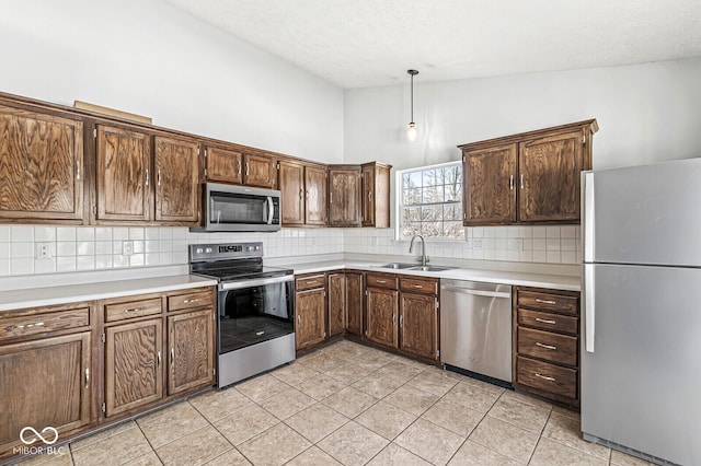 kitchen with stainless steel appliances, a sink, light countertops, and pendant lighting