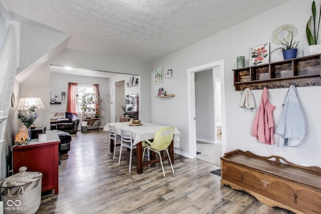 dining room featuring a textured ceiling, baseboards, and wood finished floors