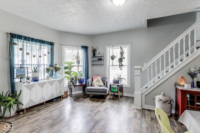 living area with wood finished floors, a textured ceiling, radiator heating unit, and stairs