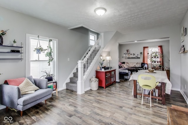 dining room with a wealth of natural light, stairway, and wood finished floors