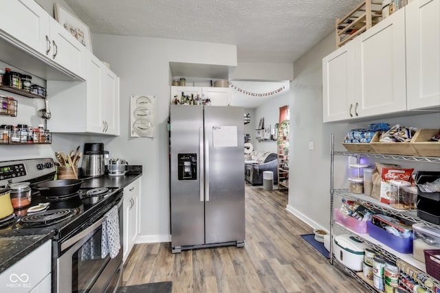 kitchen featuring stainless steel appliances, light wood-style floors, white cabinets, a textured ceiling, and baseboards