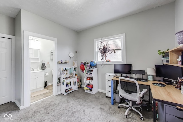 carpeted office featuring a sink and baseboards