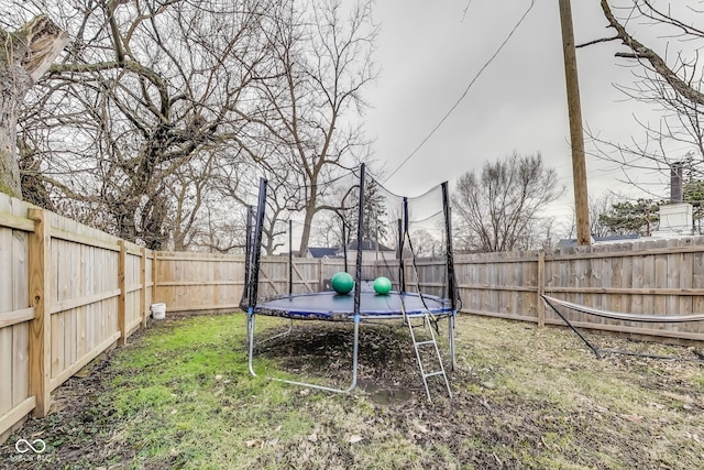 view of yard featuring a trampoline and a fenced backyard