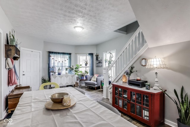 dining area featuring stairway, a textured ceiling, and wood finished floors