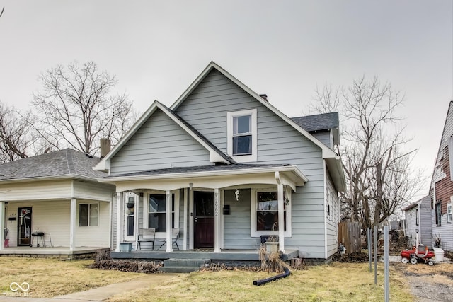 bungalow-style house with a shingled roof, a front yard, and covered porch