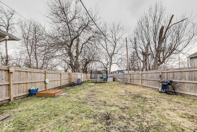 view of yard with a trampoline and a fenced backyard