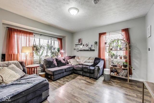 living room featuring a textured ceiling, wood finished floors, and baseboards