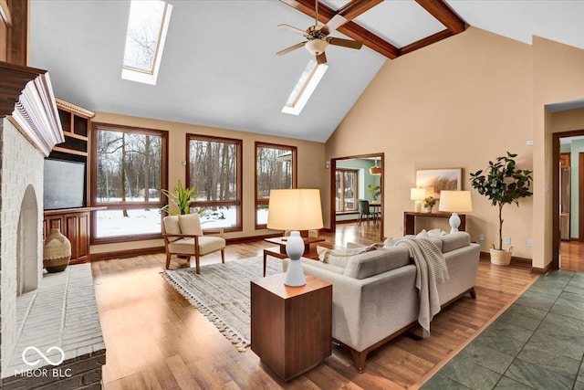 living room with hardwood / wood-style floors, high vaulted ceiling, ceiling fan, and a skylight