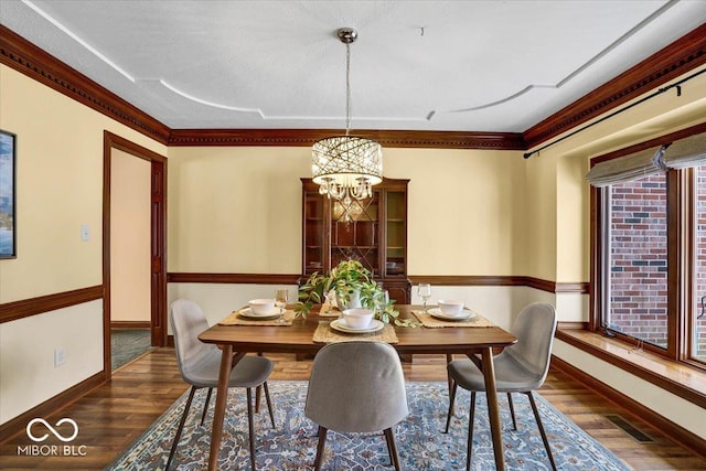 dining area with an inviting chandelier, dark hardwood / wood-style floors, and ornamental molding