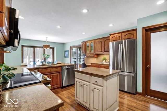 kitchen with sink, a center island, pendant lighting, light hardwood / wood-style floors, and stainless steel appliances