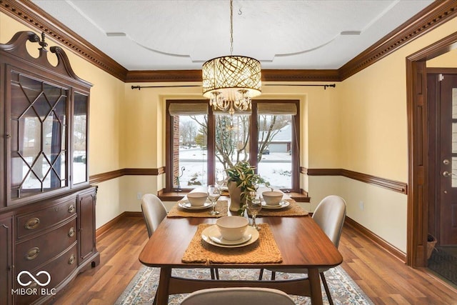 dining space featuring ornamental molding, a chandelier, and hardwood / wood-style floors