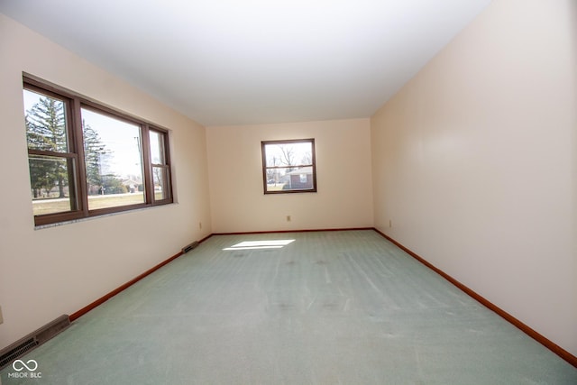 spare room with visible vents, baseboards, and light colored carpet