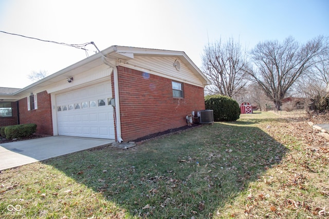 view of side of home featuring a lawn, driveway, cooling unit, an attached garage, and brick siding