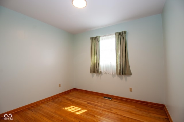 unfurnished room with light wood-type flooring, visible vents, and baseboards