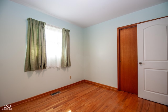 spare room featuring light wood-style floors, visible vents, and baseboards