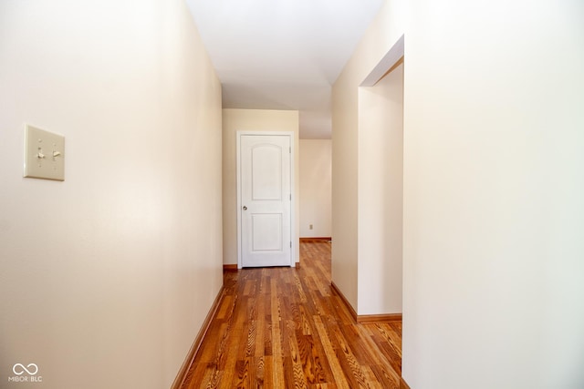 corridor with baseboards and wood finished floors