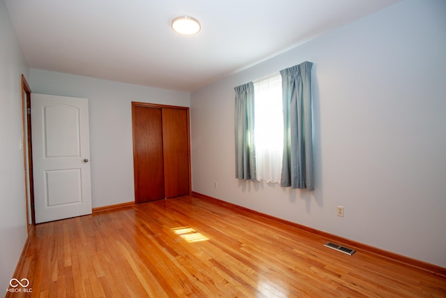 unfurnished bedroom with a closet, visible vents, light wood-type flooring, and baseboards