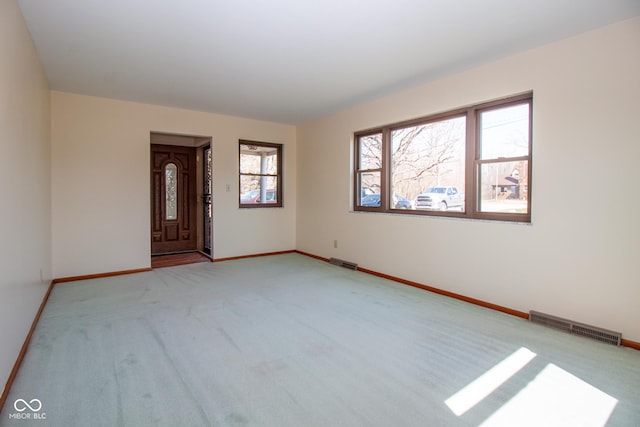 empty room with visible vents, baseboards, and light colored carpet