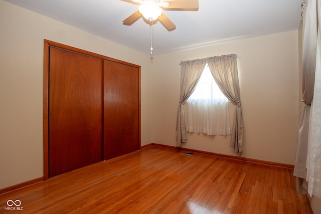 unfurnished bedroom with a ceiling fan, baseboards, visible vents, light wood finished floors, and a closet