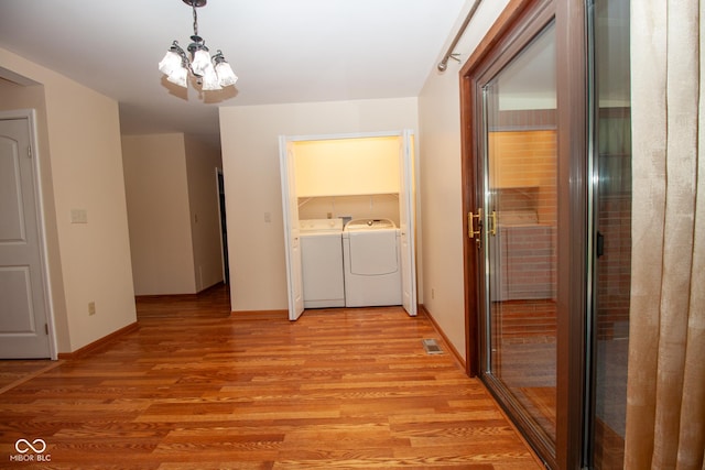 hallway featuring light wood finished floors, visible vents, baseboards, a notable chandelier, and independent washer and dryer