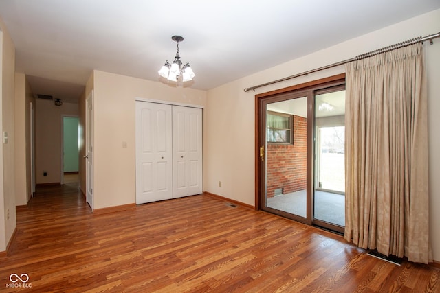 unfurnished bedroom with visible vents, light wood-style floors, a closet, access to outside, and a notable chandelier